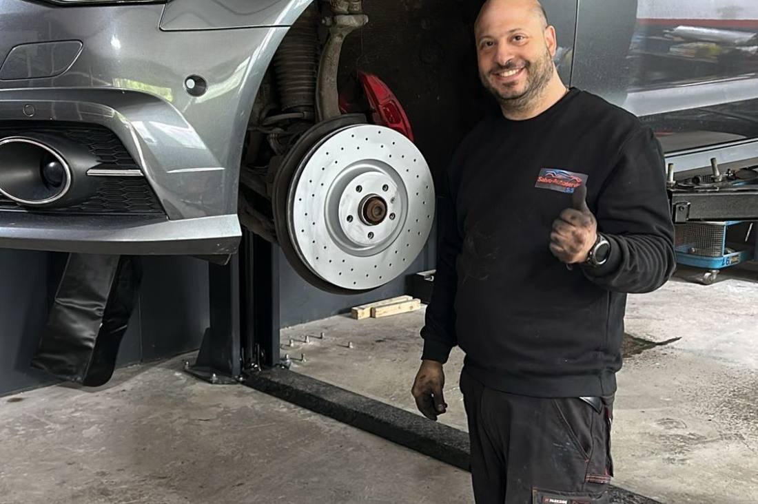Salvatore neben einem Fahrzeug auf der Hebebühne mit neuer Bremsscheibe