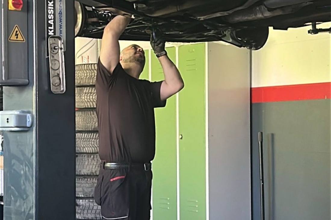 Mechaniker arbeitet am Unterboden eines Fahrzeugs